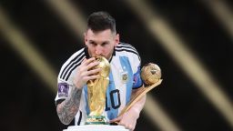 LUSAIL CITY, QATAR - DECEMBER 18: Lionel Messi of Argentina kisses the FIFA World Cup Qatar 2022 Winner's Trophy while holding the adidas Golden Boot award after the FIFA World Cup Qatar 2022 Final match between Argentina and France at Lusail Stadium on December 18, 2022 in Lusail City, Qatar. (Photo by Julian Finney/Getty Images)