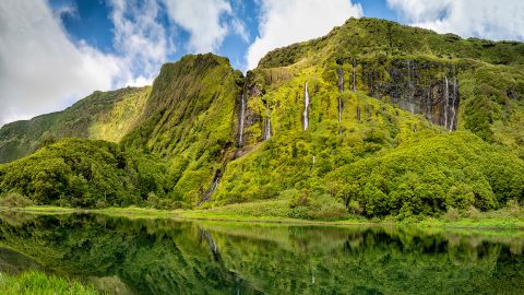 Waterfalls trickle down an imposing rock face on the island Flores in the Azores.
