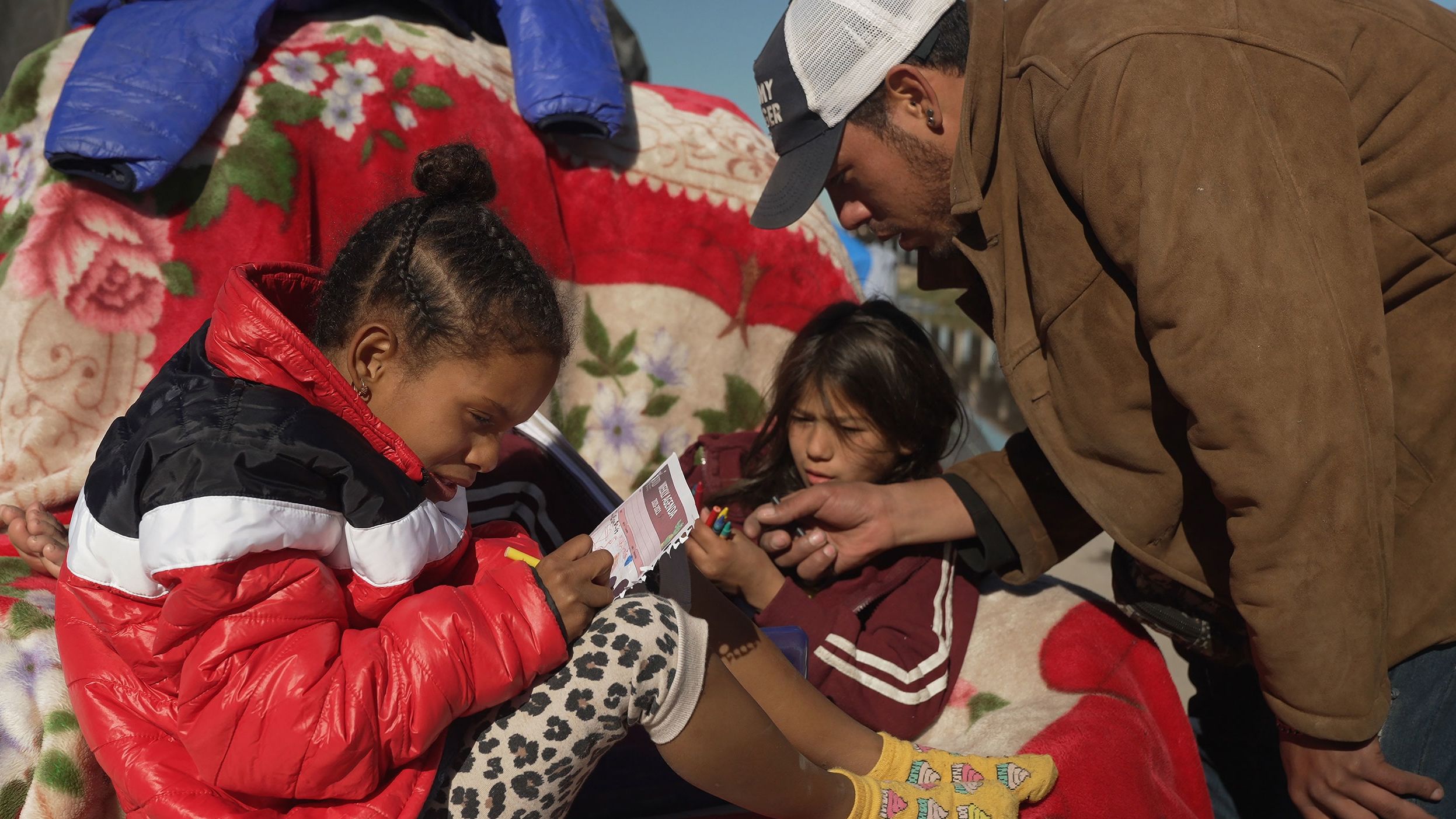 Francisco Mota plays with his children at an improvised camp of migrants, mostly from Venezuela, next to the Rio Grande river in Ciudad Juarez at the Mexico-US border in November of 2022. 