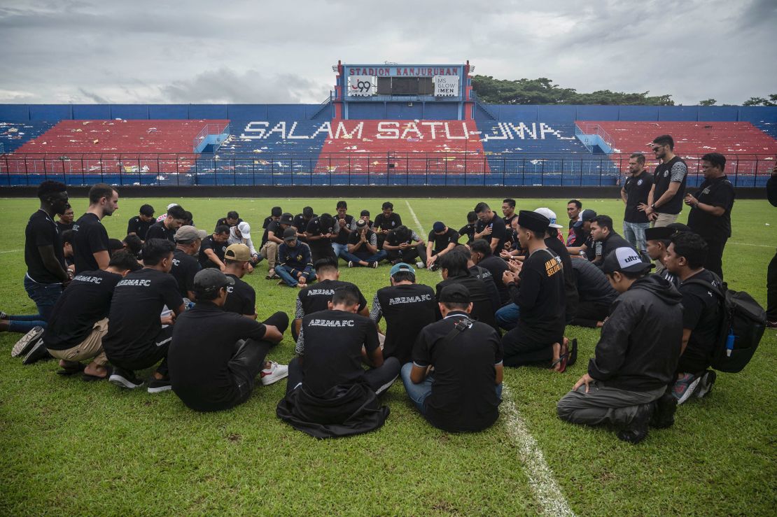 Players and officials from Arema Football Club gather to pray on the pitch for victims of the stampede at Kanjuruhan stadium in Malang.