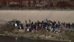 A group of migrants waits on the US side of the Rio Grande as the Texas National Guard blocked access to parts of the border with barbed wire and vehicles as seen from Ciudad Juarez, Mexico, on December 20, 2022. 