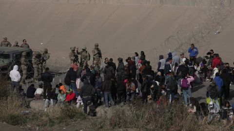 A group of migrants wait on the US side of the Rio Grande as the Texas National Guard blocks access to parts of the border with barbed wire and vehicles, seen from Ciudad Juarez, Mexico, December 20, 2022 .