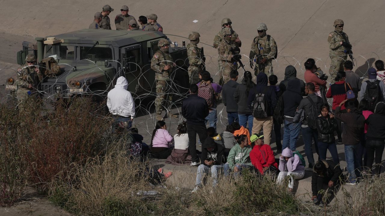 A group of migrants are waiting on the US side of the Rio Grande as the Texas National Guard blocked access to parts of the border with barbed wire and vehicles as seen from Ciudad Juarez, Mexico, on December 20, 2022.