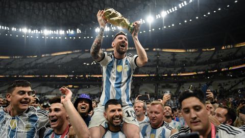 LUSAIL CITY, QATAR - DECEMBER 18: Lionel Messi of Argentina celebrates with the FIFA World Cup Qatar 2022 Winner's Trophy on Sergio 'Kun' Aguero's shoulders after the team's victory during the FIFA World Cup Qatar 2022 Final match between Argentina and France at Lusail Stadium on December 18, 2022 in Lusail City, Qatar.  (Photo by David Ramos - FIFA/FIFA via Getty Images)
