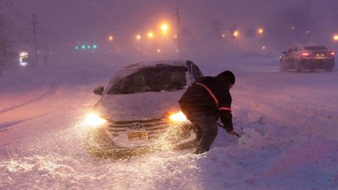 A driver shovels his car out of a snow pile in Barnegat Township, New Jersey, as he heads to work on Tuesday.