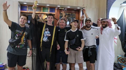 An Argentinian fan raises a mock World Cup trophy as he wears a traditional black and gold Arab cloak (bisht) during a group picture in Doha's Souq Waqif market in Qatar, on Tuesday.