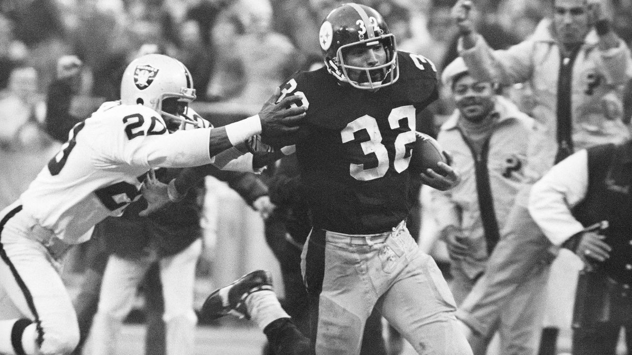 Franco Harris (32) eludes a tackle by Oakland Raiders' Jimmy Warren as the Pittsburgh Steelers running back runs 42-yards for a touchdown after catching a deflected pass during an AFC Divisional NFL football playoff game in Pittsburgh on Dec. 23, 1972.