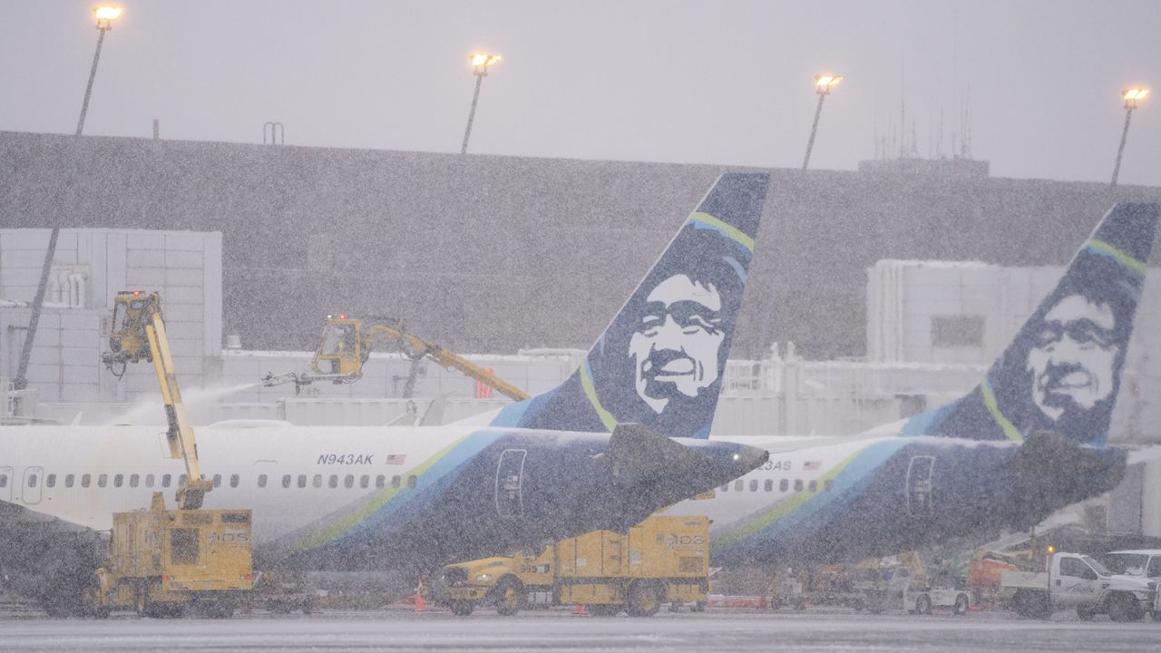 Workers deice an Alaska Airlines plane during a snow storm at Seattle-Tacoma International Airport (SEA) in Seattle, Washington, US, on Tuesday, Dec. 20, 2022. An estimated 112.7 million people will travel 50 miles or more from Dec. 23 to Jan. 2, up by 3.6 million from last year and getting close to pre-pandemic levels, according to AAA, a provider of travel insurance. Photographer: David Ryder/Bloomberg via Getty Images