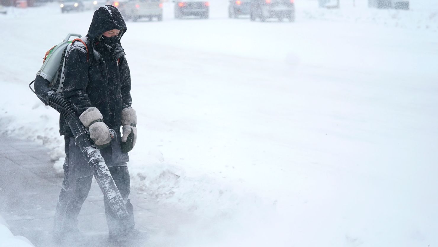 A man blows snow off a sidewalk Wednesday, December 21, 2022, in Minneapolis.