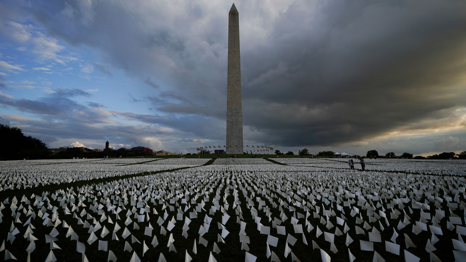 With the Washington Monument in the background, people look at white flags that are part of artist Suzanne Brennan Firstenberg's temporary art installation, "In America: Remember," in remembrance of Americans who have died of Covid-19.