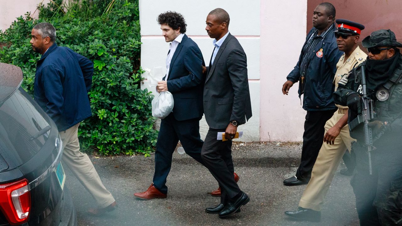 Sam Bankman-Fried, founder of FTX, second left, is escorted out of the Magistrate's Court in Nassau, Bahamas, on Wednesday, Dec. 21, 2022. Bankman-Fried is on his way to an airport to be flown to the US to face a litany of criminal charges after a Bahamas judge approved his extradition. 