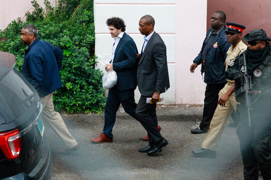 Sam Bankman-Fried, founder of FTX, second left, is escorted out of the Magistrate's Court in Nassau, Bahamas, on Wednesday, Dec. 21, 2022. Bankman-Fried is on his way to an airport to be flown to the US to face a litany of criminal charges after a Bahamas judge approved his extradition. 