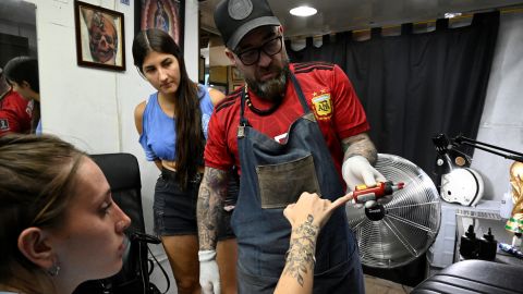 Sebastian Arguello Paz shows red ink to Florencia Sola, 26, before tattooing her with a number 10, honouring Messi.