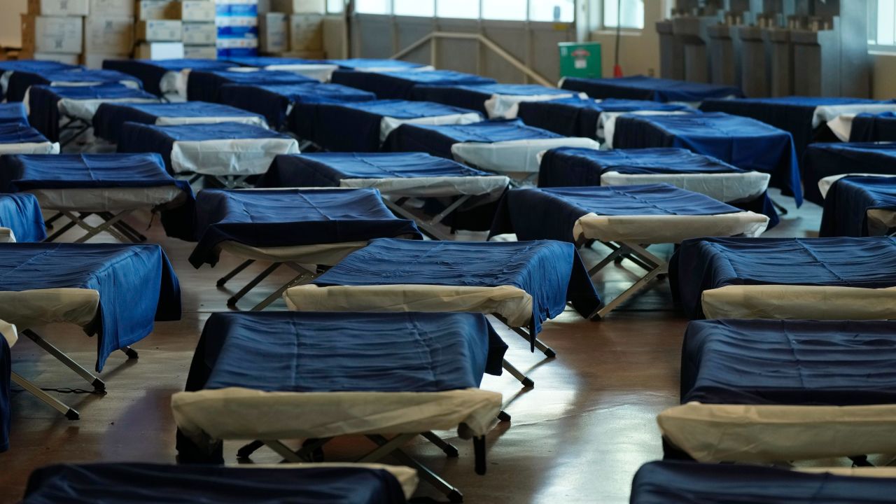 Lines of cots for people seeking refuge from the intense cold front sweeping over the intermountain West fill the walkways in the Denver Coliseum Wednesday, December 21, 2022.