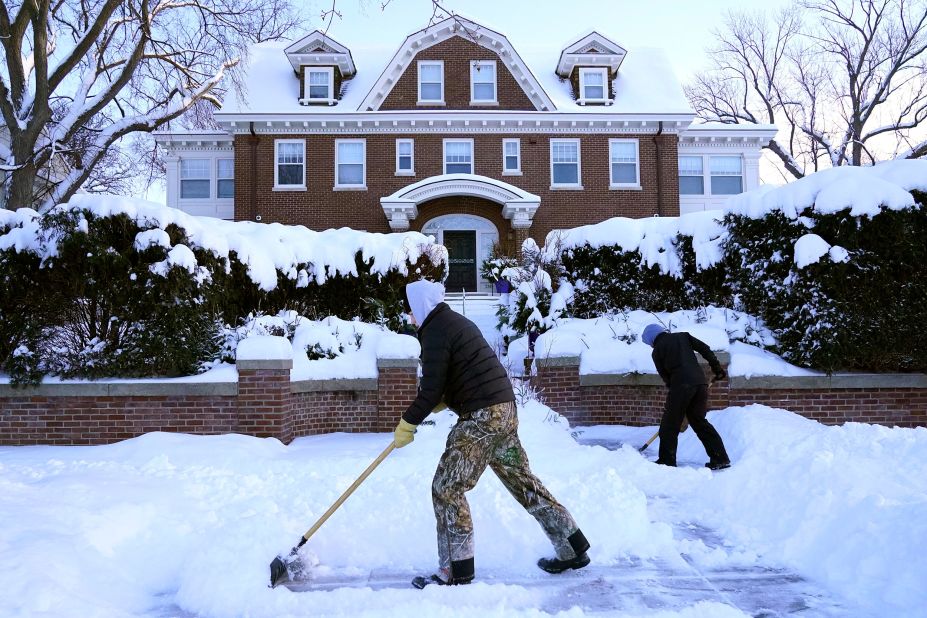 Kids shovel snow off a sidewalk and driveway in Minneapolis on December 22.
