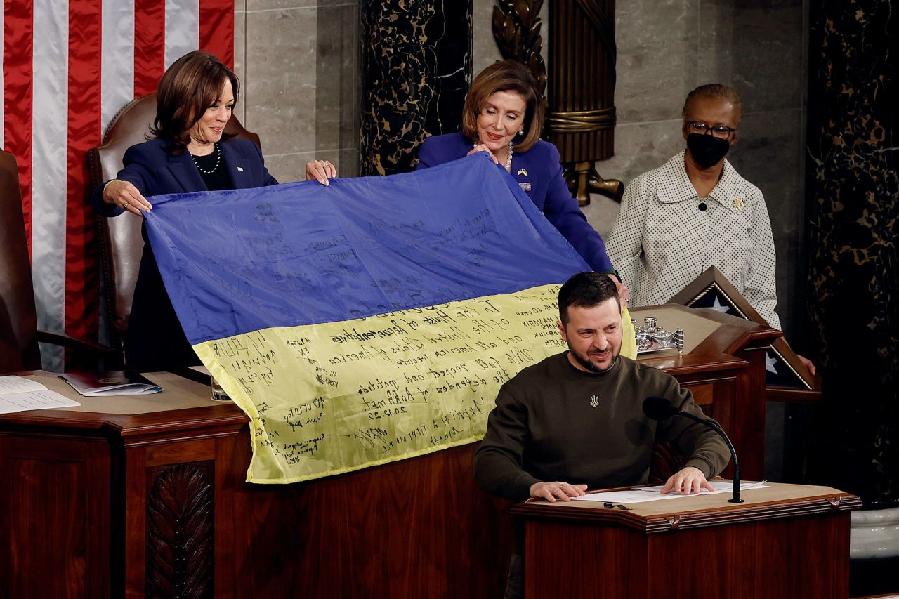 Ukrainian President Volodymyr Zelensky addresses Congress at the US Capitol in Washington as House Speaker Nancy Pelosi and Vice President Kamala Harris hold up a Ukrainian national flag signed by troops from the besieged area of Bakhmut on Wednesday, December 21.