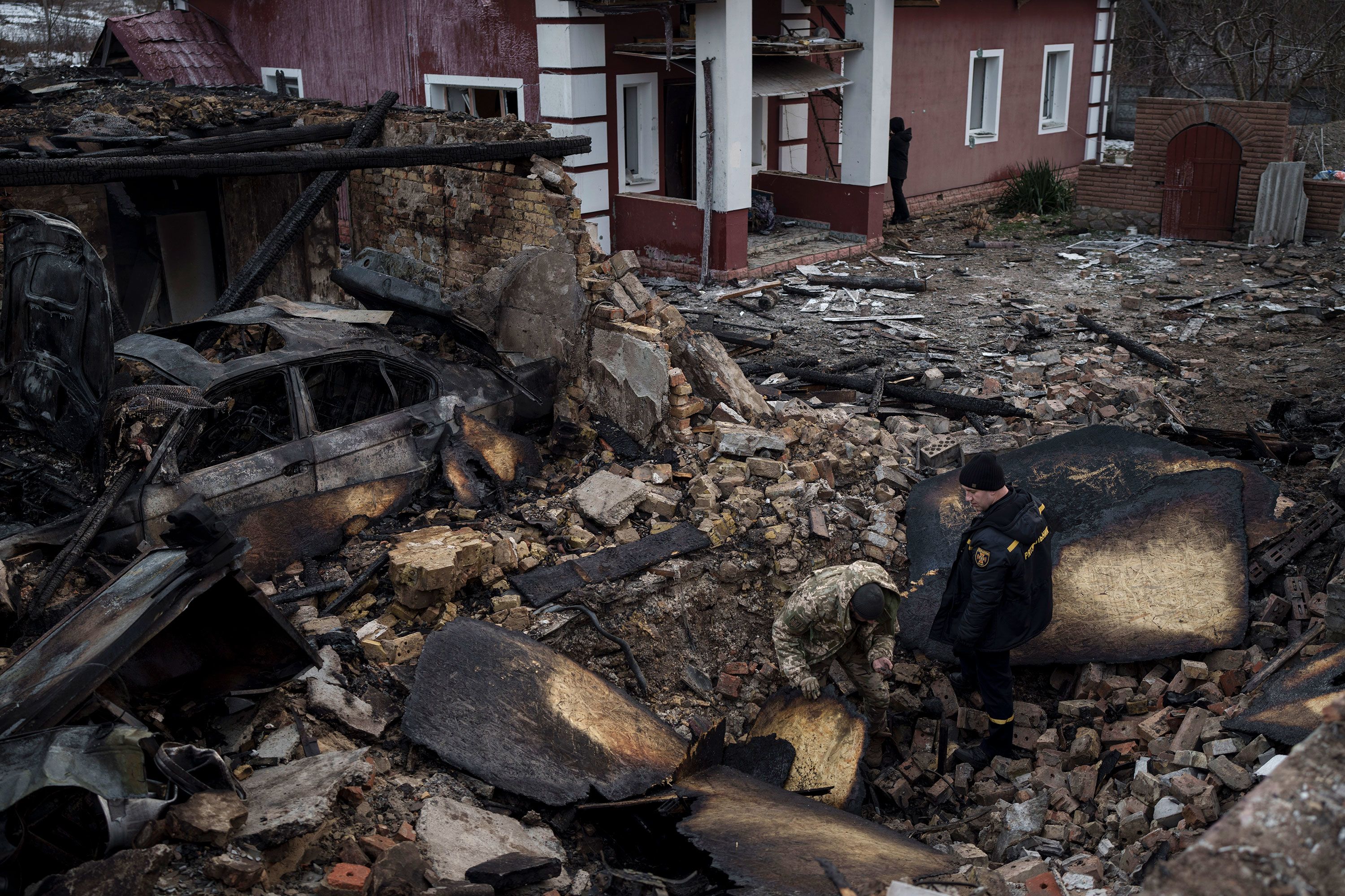 A Ukrainian firefighter and serviceman inspect a house damaged by a Russian drone attack in Stari Bezradychi, Ukraine, on Monday, December 19.