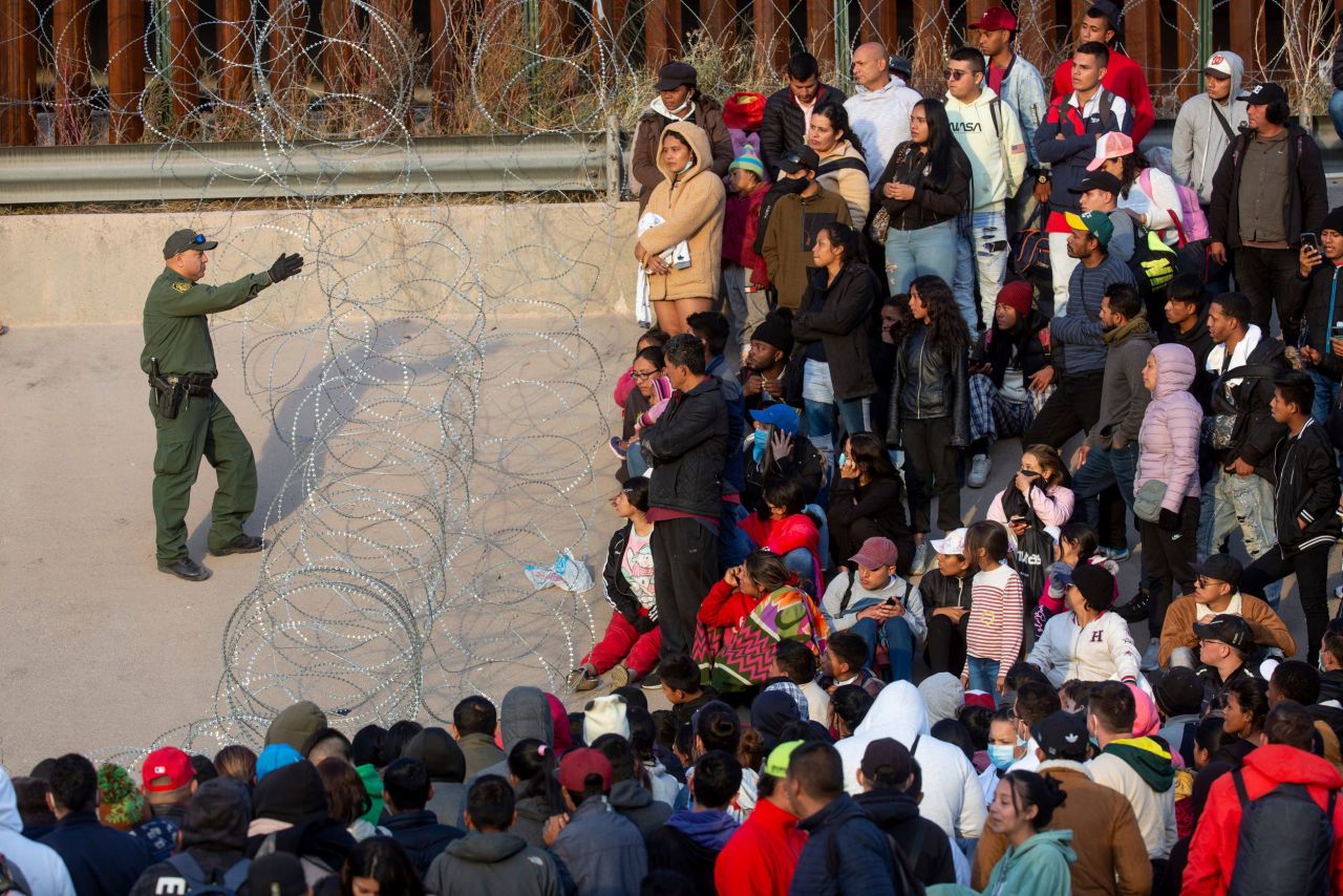 Migrants who crossed the Rio Grande approach the Texas National Guard to inquire when they will be allowed to be processed by Customs and Border Protection to seek asylum in El Paso, Texas, on Tuesday, December 20.