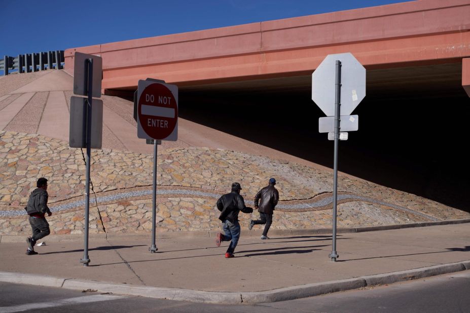 Migrants run into the street after crossing into the United States through a hole in an El Paso fence on December 22.
