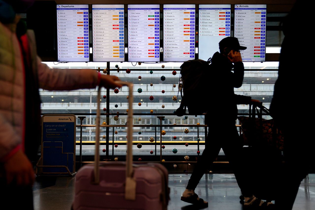 Travelers walk in front of flight information screens at O'Hare International Airport in Chicago on December 22.