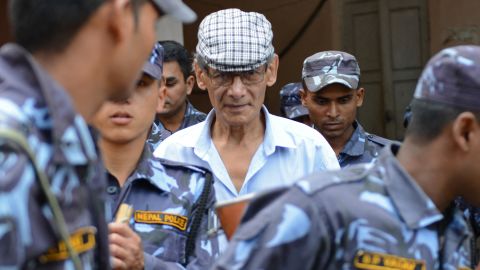 A polícia nepalesa escolta Sobhraj em um tribunal distrital em Bhaktapur em 12 de junho de 2014.