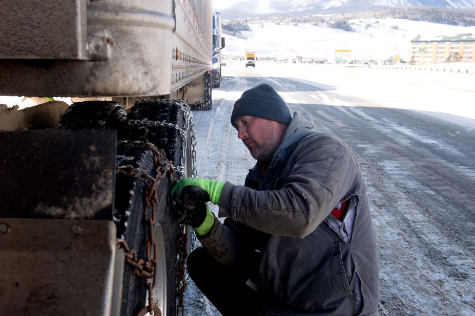 Robert Arnold puts chains onto the tires of his semitrailer while he waits for the eastbound lane of I-70 to reopen in Silverthorne, Colorado, on December 22.