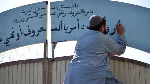 A member of the Taliban replaces a sign from the Department of Women's Affairs with one from the Ministry of Promotion of Virtue and Prevention of Vice at a government building in Kandahar, Afghanistan, in October 2021.