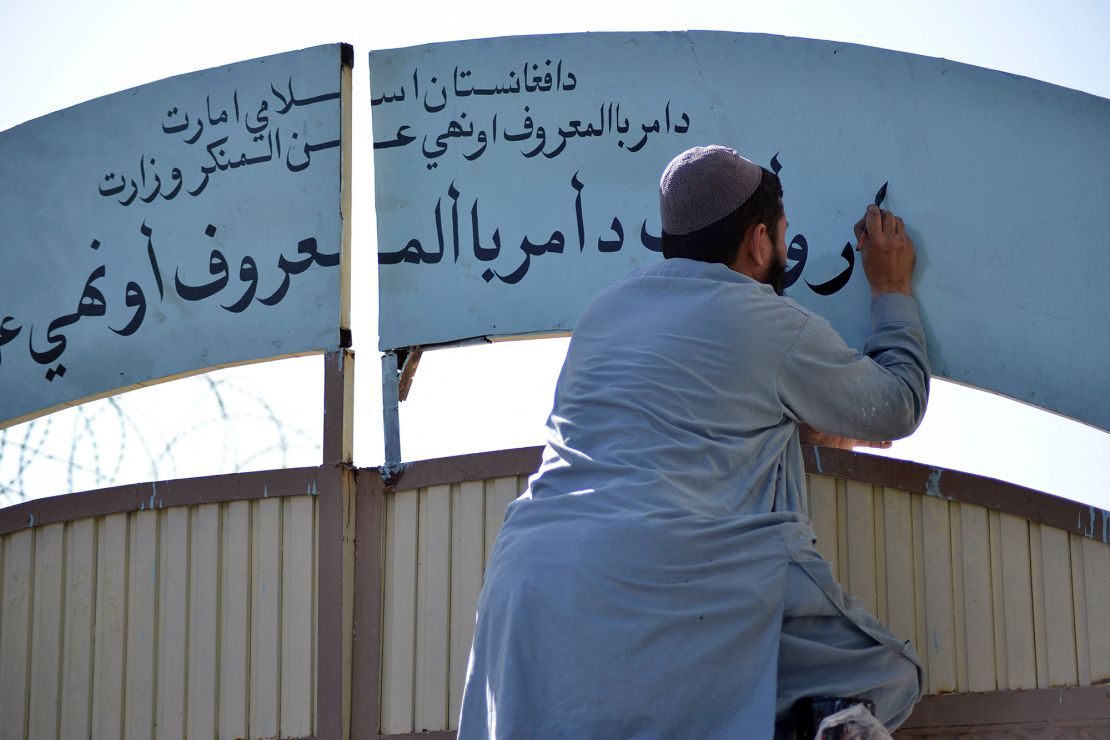 A member of the Taliban replaces a sign of the Department for Women's Affairs with one of the Ministry for the Promotion of Virtue and Prevention of Vice at a government building in Kandahar, Afghanistan, in October 2021.