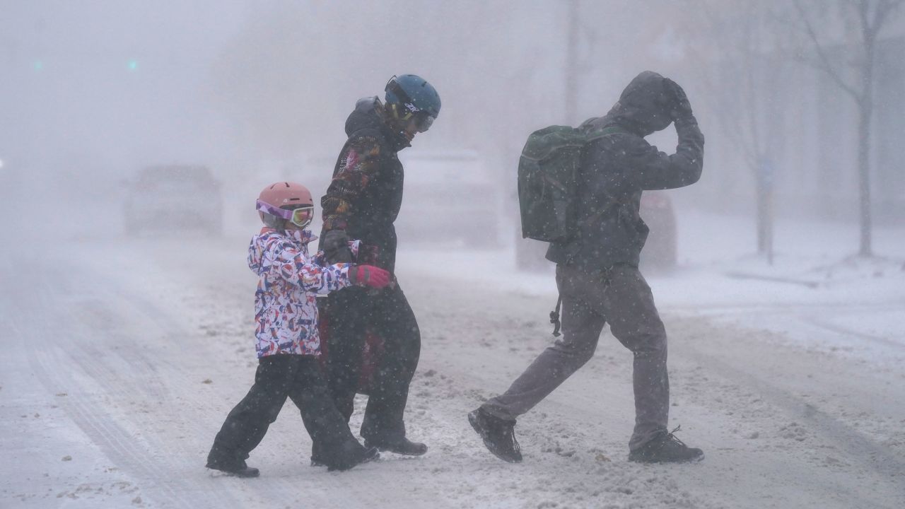 The Firestone family makes their way across Elmwood Avenue in Buffalo, N.Y. after stocking up on supplies at the grocery store, Friday, Dec. 23, 2022. Winter weather is blanketing the U.S. as a massive storm sent temperatures crashing and created whiteout conditions.(Derek Gee /The Buffalo News via AP)