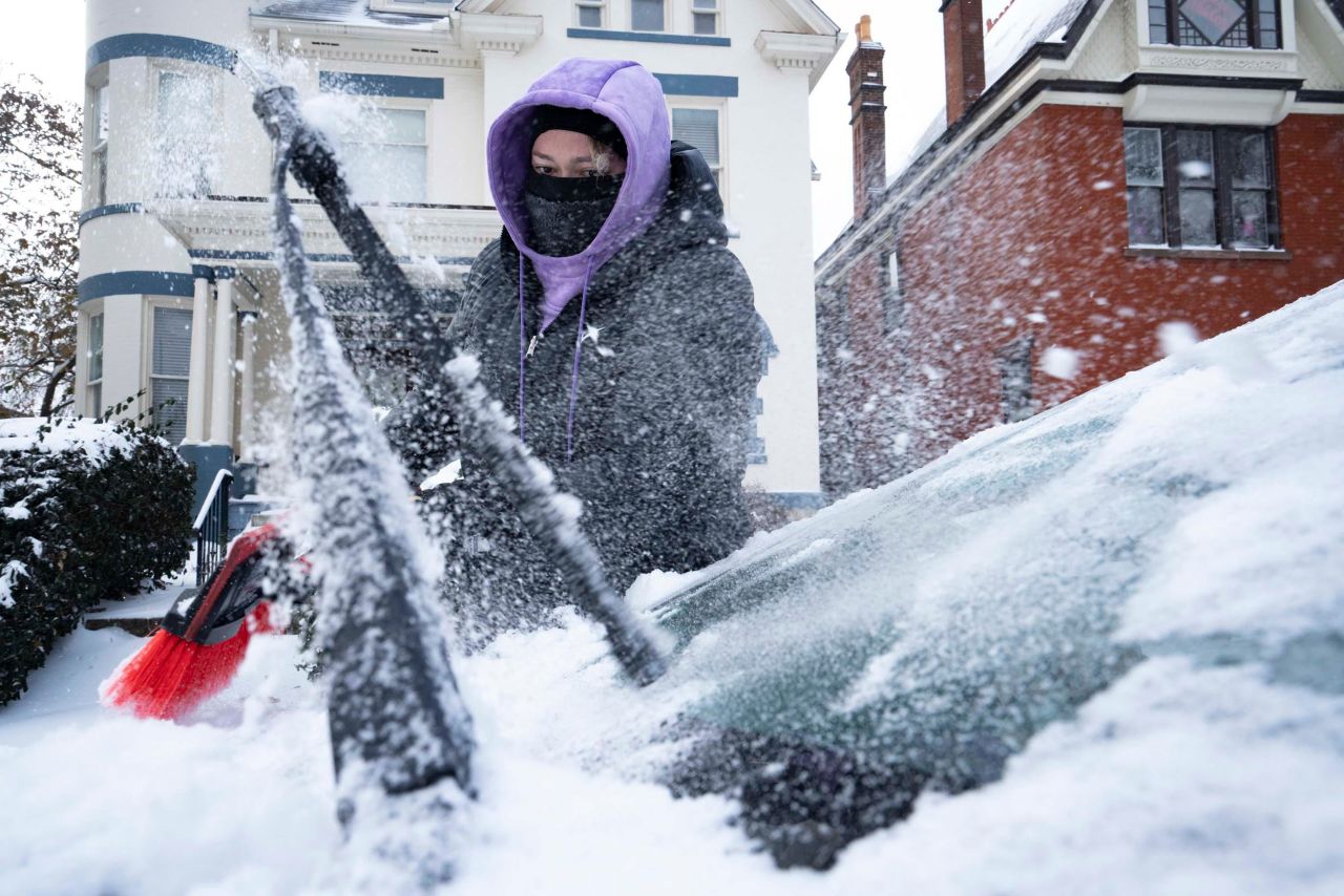 Amanda Kelly cleans off snow and ice from her car on Friday, December 23, in Columbus, Ohio.