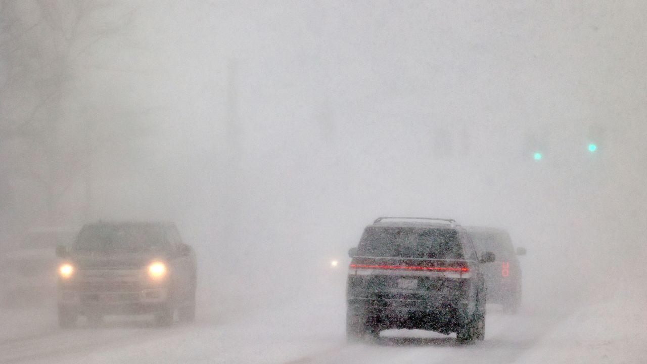 Cars drive in whiteout conditions in Orchard Park, N.Y. Friday, Dec. 23, 2022. Winter weather is blanketing the U.S. as a massive storm sent temperatures crashing and created whiteout conditions. (Mark Mulville /The Buffalo News via AP)