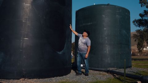 Benjamin Cuevas stands next to a town water tank in Tooleville.