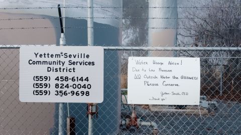 A water usage notice is posted on a fence surrounding the Yettem-Seville water storage tanks.