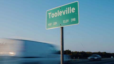 Cars drive past a sign on the outskirts of Tooleville.