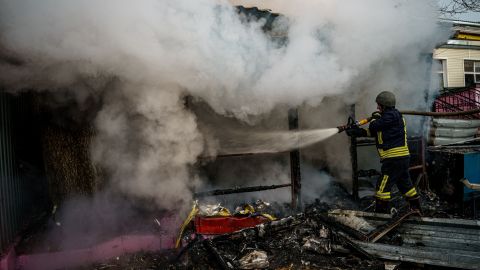 A rescuer extinguishes a fire in a burning shop after Russian shelling on the city of Kherson on December 24, 2022.