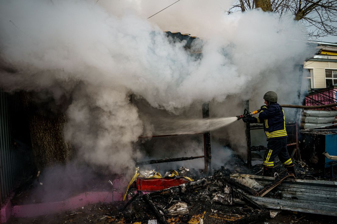 A rescuer extinguishes a fire in a burning shop after Russian shelling on the city of Kherson on December 24, 2022.