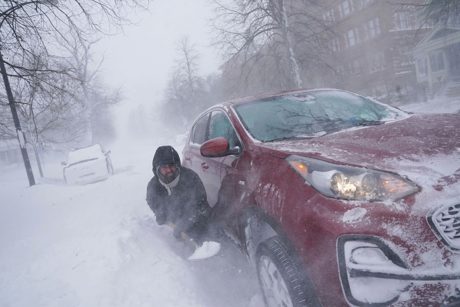 A man tries to dig out his car after he got stuck in a snowdrift about a block from home in Buffalo on Saturday, December 24.