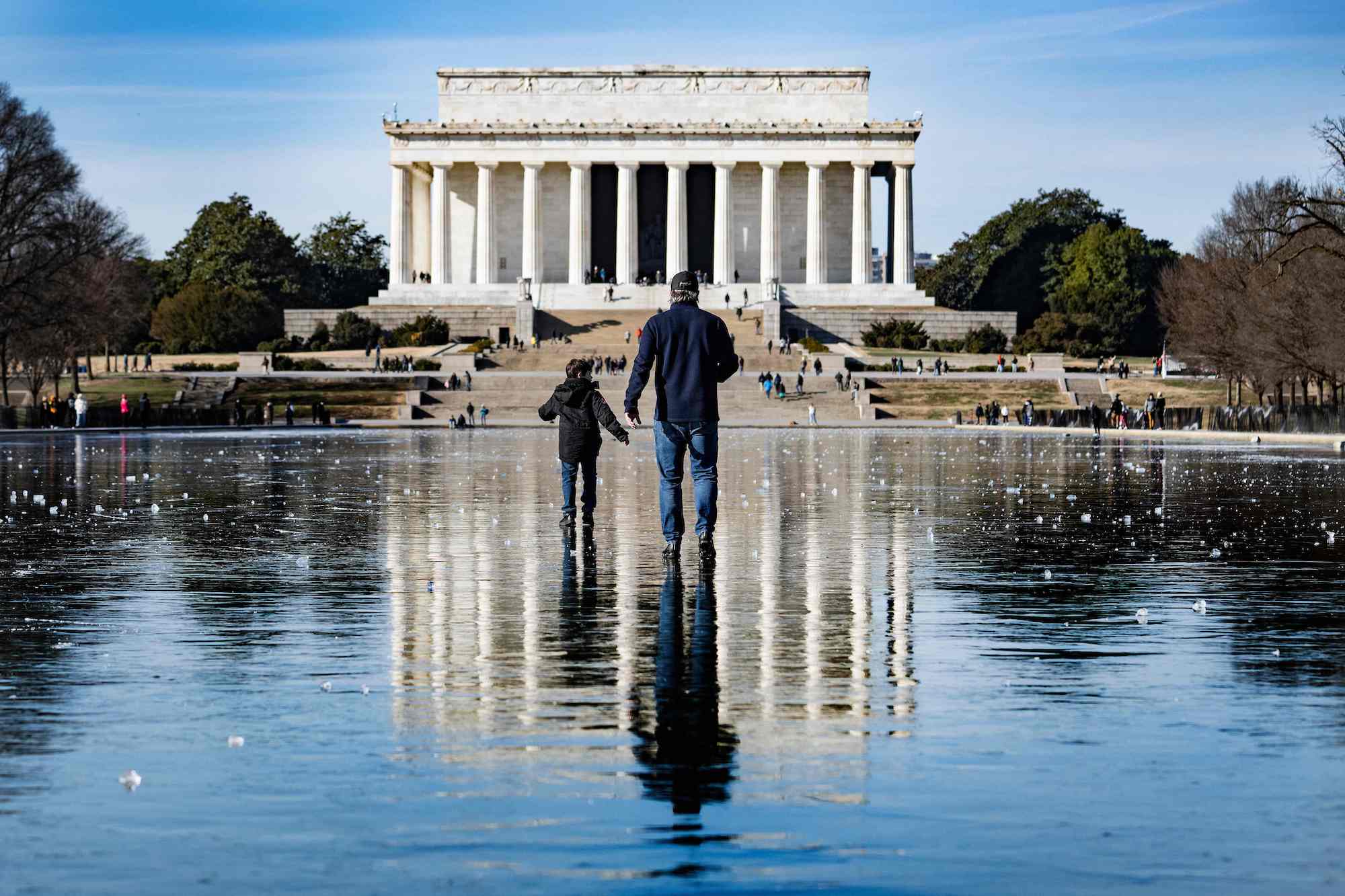 A man and a boy walk across the frozen Reflecting Pool towards the Lincoln Memorial in Washington, DC, on December 26.