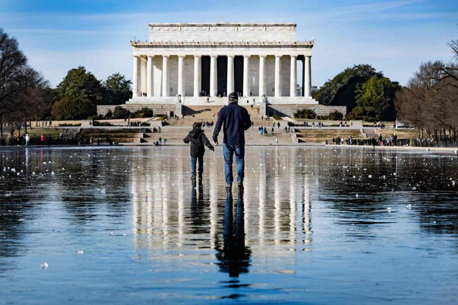 A man and a boy walk across the frozen Reflecting Pool towards the Lincoln Memorial in Washington, DC, on December 26.