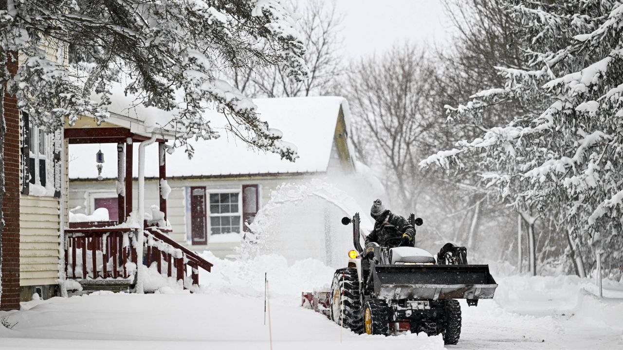 A person clears snow-covered roads with a backhoe loader in Buffalo, New York, United States on December 26, 2022.
