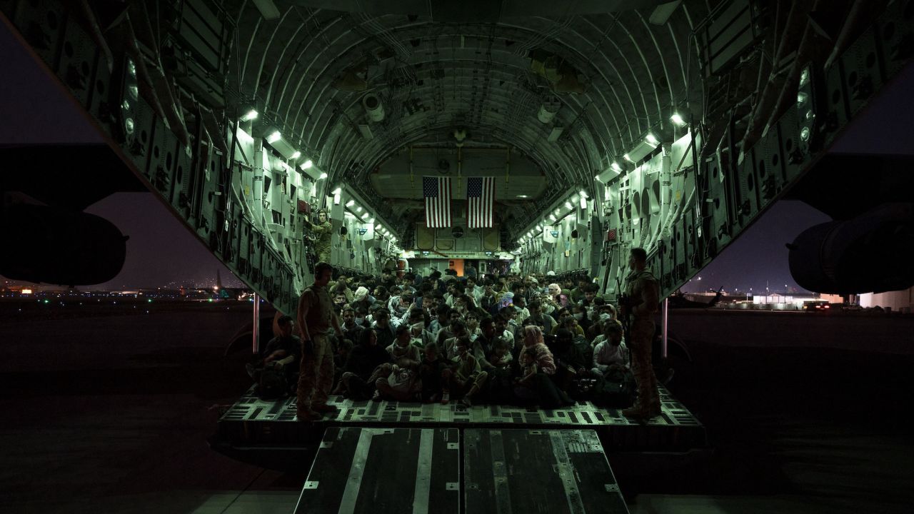 A US Air Force crew assists evacuees aboard a  C-17 Globemaster III aircraft in support of the Afghanistan evacuation at Hamid Karzai International Airport, Afghanistan, Aug. 21, 2021.  