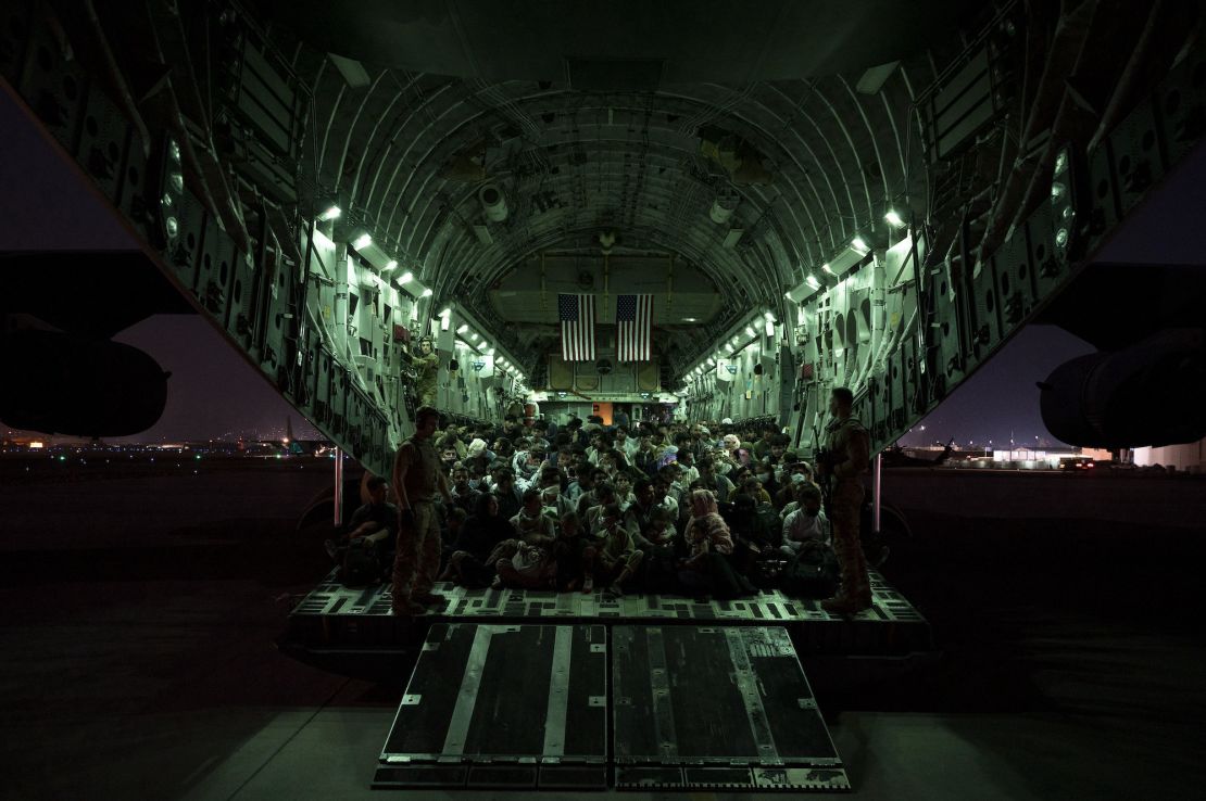 A US Air Force crew assists evacuees aboard a  C-17 Globemaster III aircraft in support of the Afghanistan evacuation at Hamid Karzai International Airport, Afghanistan, Aug. 21, 2021.  