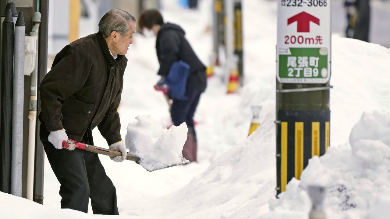 Residents shovel snow off a sidewalk in Kanazawa, Ishikawa prefecture, central Japan, on December 24, 2022.