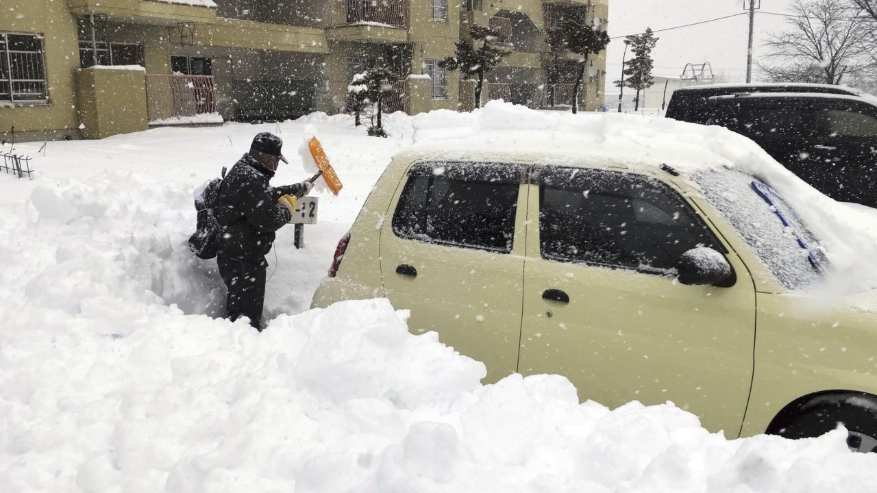 A man shovels snow off a car in Hokkaido, Japan, on December 24 2022.