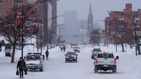 People and vehicles move about Main St. in Buffalo, on December 26, 2022, after a massive snow storm blanketed the city. 