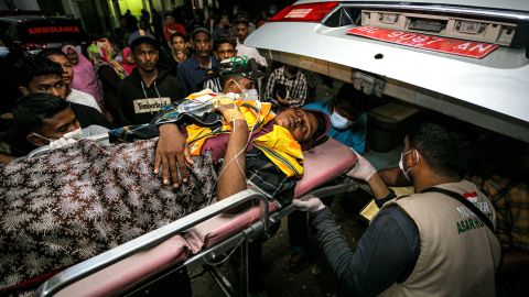 A volunteer and a soldier transports a Rohingya woman onto an ambulance heading to a new shelter in the Muara Tiga district in Pidie, Aceh province on December 26, 2022.