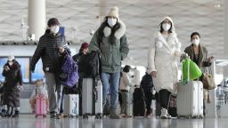 Passengers wearing face masks pull baggage at a departure lobby in Beijing Capital International Airport on Dec. 27, 2022, after the central government recently dropped its "zero-COVID" policy. 