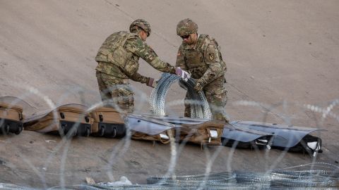 Texas National Guard troops unroll coils of concertina wire Wednesday near the US-Mexican near Ciudad Juarez.