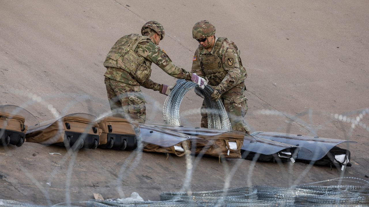 Texas National Guard troops unroll coils of concertina wire Wednesday near the US-Mexican border near Ciudad Juarez.