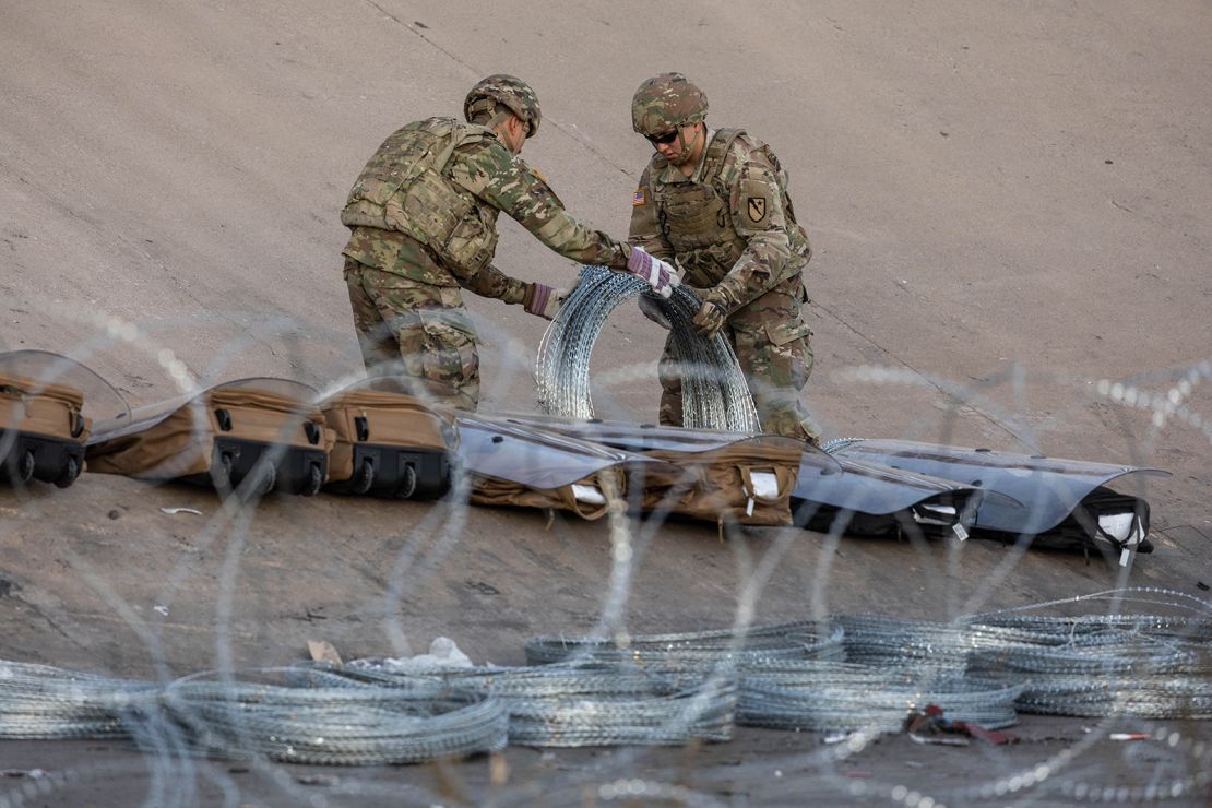 Texas National Guard troops unroll coils of concertina wire Wednesday near the US-Mexican border near Ciudad Juarez.